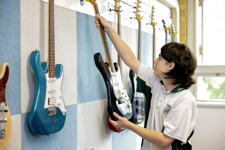 student seleciting an electric guitar from a wall