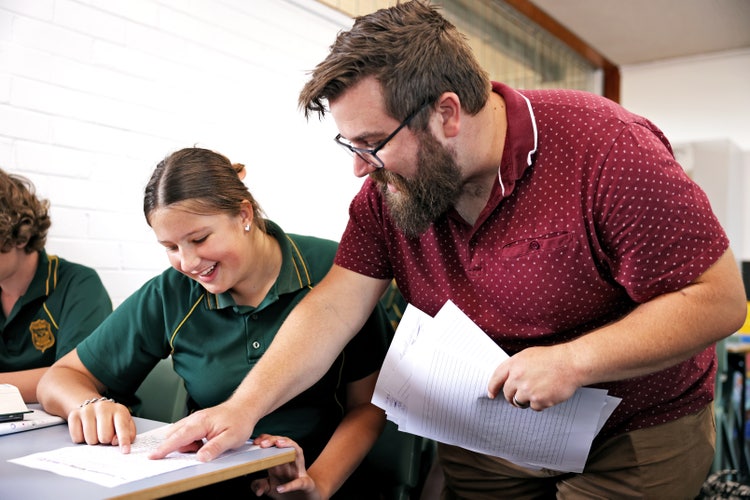 teacher helping student in classroom
