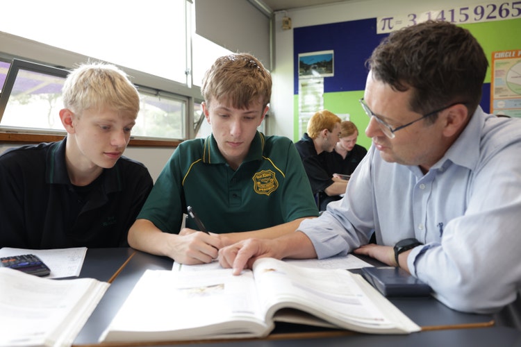 A junior and a senior maths student are working with their teacher.