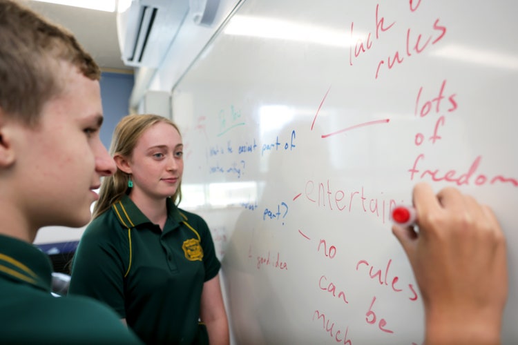 Two students stand by a whiteboard brainstorming ideas.