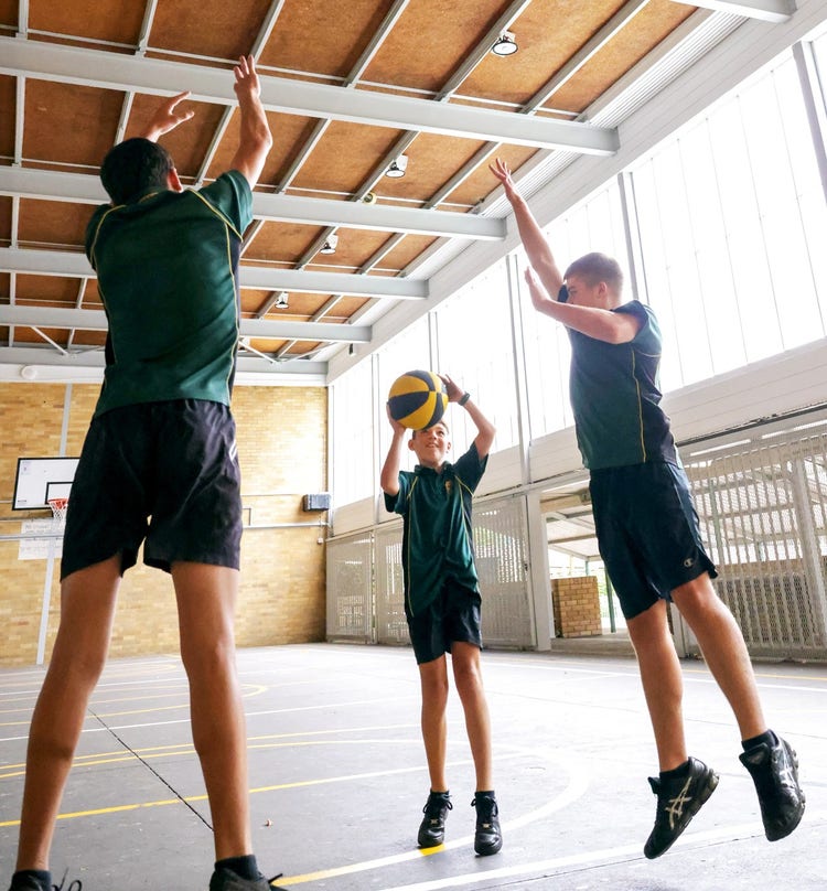 three students playing basketball